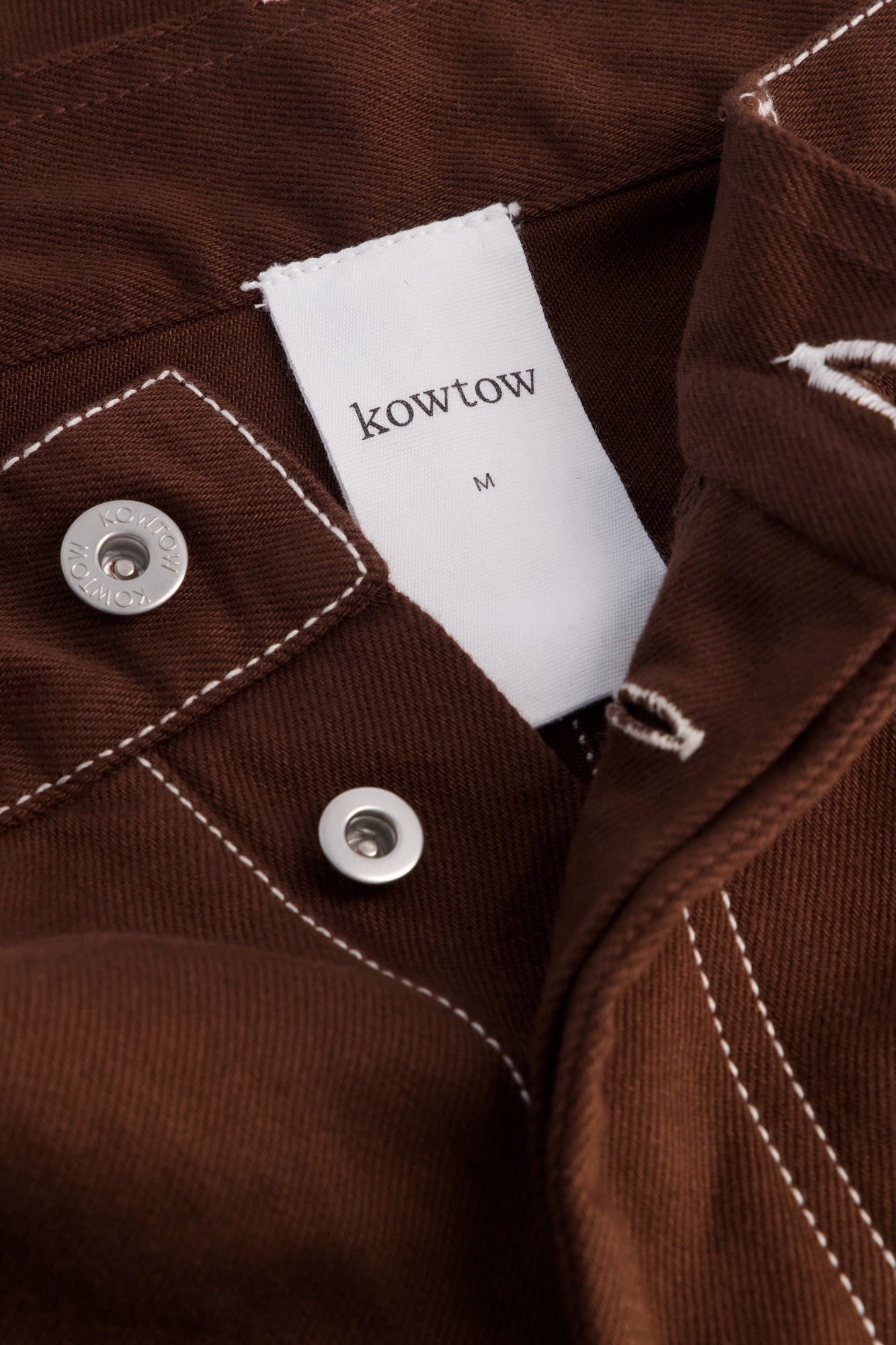 Kowtow Unity Jeans in brown denim close up interior label and metal button detail