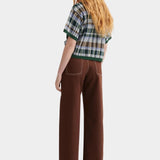 Kowtow Unity Jeans in brown denim worn with plaid knit top, full length back view