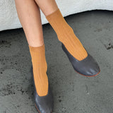 Le Bon Shoppe Peanut Butter Her Socks styled with charcoal leather flats, showing warm caramel color and ribbed texture