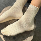 Side view of Porcelain ribbed cotton socks styled on feet showing stretch, texture and quarter crew height