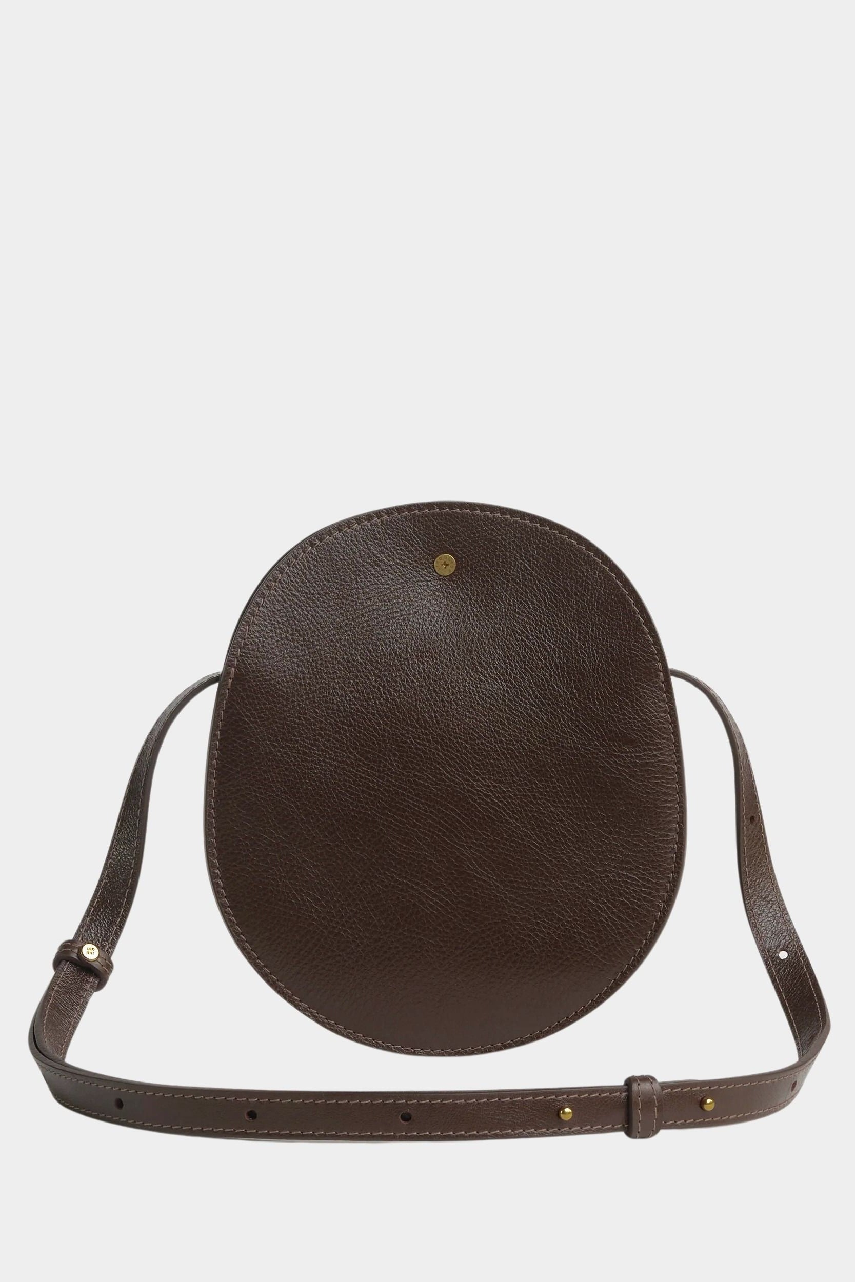 Chaga Eggi bag standing upright with its adjustable strap arranged around the base and brass closure visible