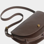 LINDQUIST Mezzo bag in Chaga laid flat with its leather strap curled beside the crescent body