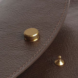 Close view of the Chaga Mezzo bag’s brass flap closure, pebbled leather, and tonal stitching