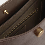 Close view of the Chaga Savoie bag’s interior zippered pocket, pebbled leather, and brass closure