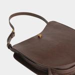 Chaga Savoie bag laid flat, showing its curved leather body, divided interior, and shoulder strap