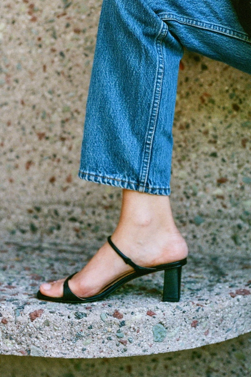 LOQ Gael black leather heeled sandal close up on foot with jeans and block heel