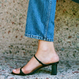 LOQ Gael black leather heeled sandal close up on foot with jeans and block heel
