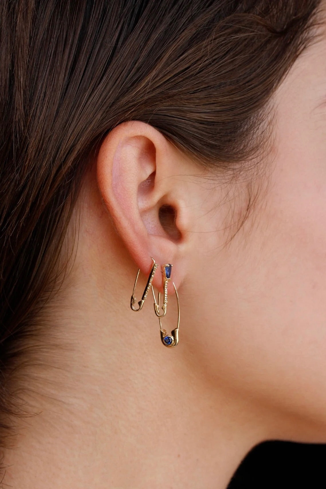 Loren Stewart Cirque Safety Pin Earring in 14k gold worn below two delicate gold earrings