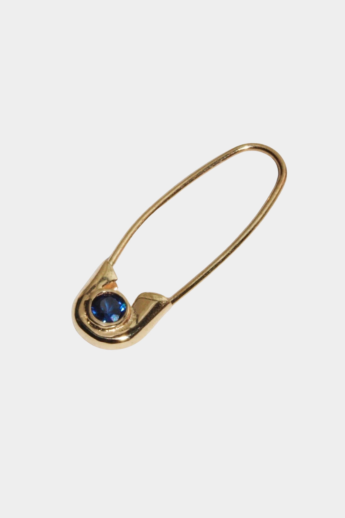 Angled close view of 14k gold Cirque Safety Pin Earring with round blue sapphire