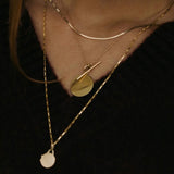Model wearing 10K gold herringbone chain necklace layered with pendant.