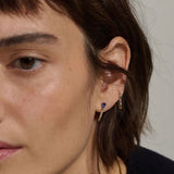 Model wearing 14K gold pear sapphire and diamond hoop earrings.