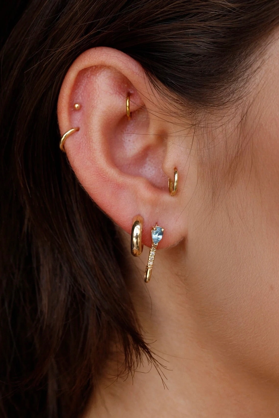 Model wearing 14K gold diamond and blue topaz drop hoop earrings.