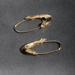 Mirrored Pisces fish earrings in 14k yellow gold displayed on gray fabric