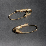 Mirrored Pisces fish earrings in 14k yellow gold displayed on gray fabric