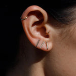 Model wearing 14K gold bar stud earrings in curated ear stack.