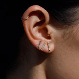 Model wearing 14K gold bar stud earrings in curated ear stack.