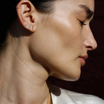Model wearing 14K gold vertical bar stud earrings.