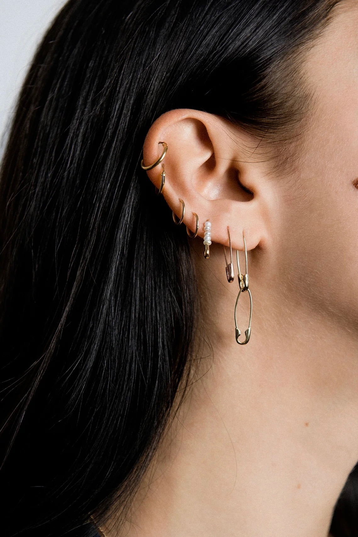 Model wearing 14K gold elongated safety pin earrings.