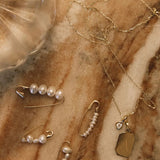 14K gold hoop earring with freshwater pearl beads styled with layered jewelry.