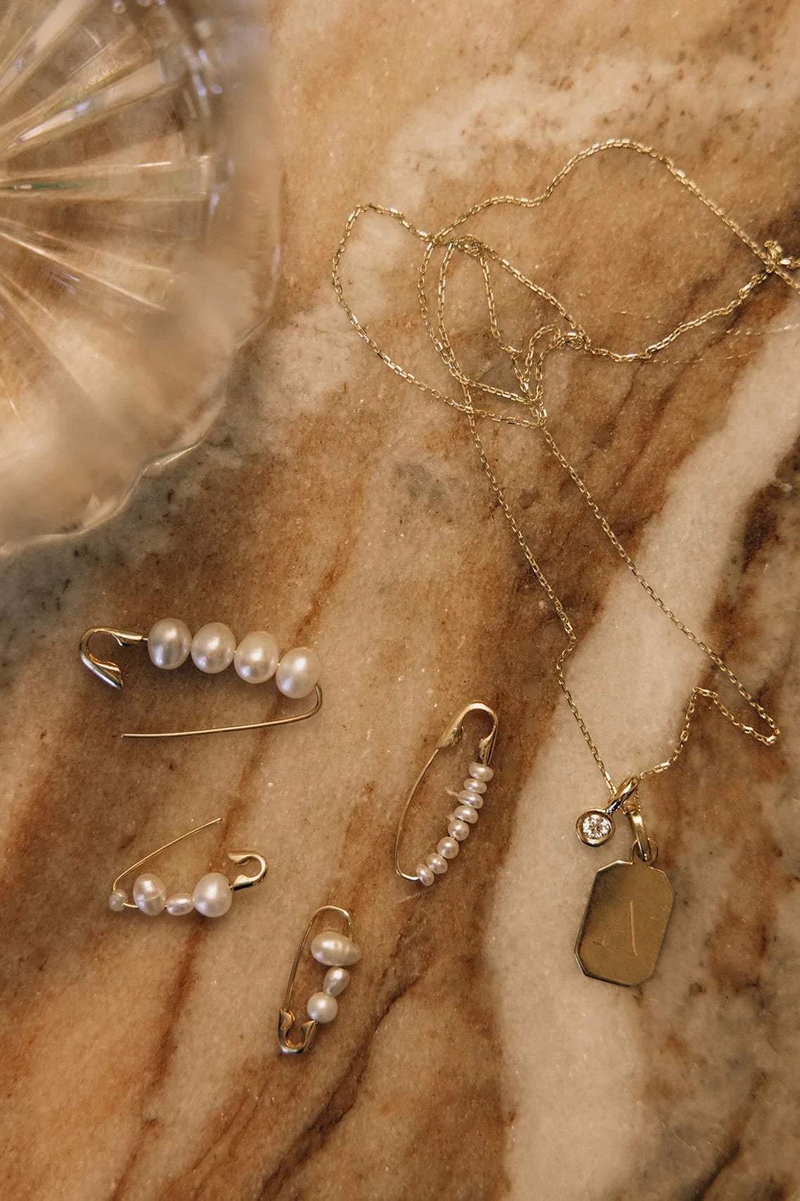 14K gold hoop earring with freshwater pearl beads styled with layered jewelry.