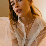 Model wearing 14K gold hoop earrings with freshwater pearl beads.