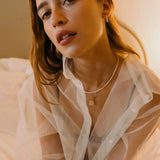Model wearing 14K gold hoop earrings with freshwater pearl beads.