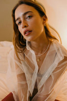 Model wearing 14K gold hoop earrings with freshwater pearl beads.