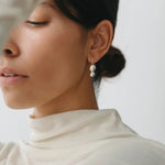 Maslo Jewelry double orb sterling silver drop earrings worn on model with neutral top, close-up side profile
