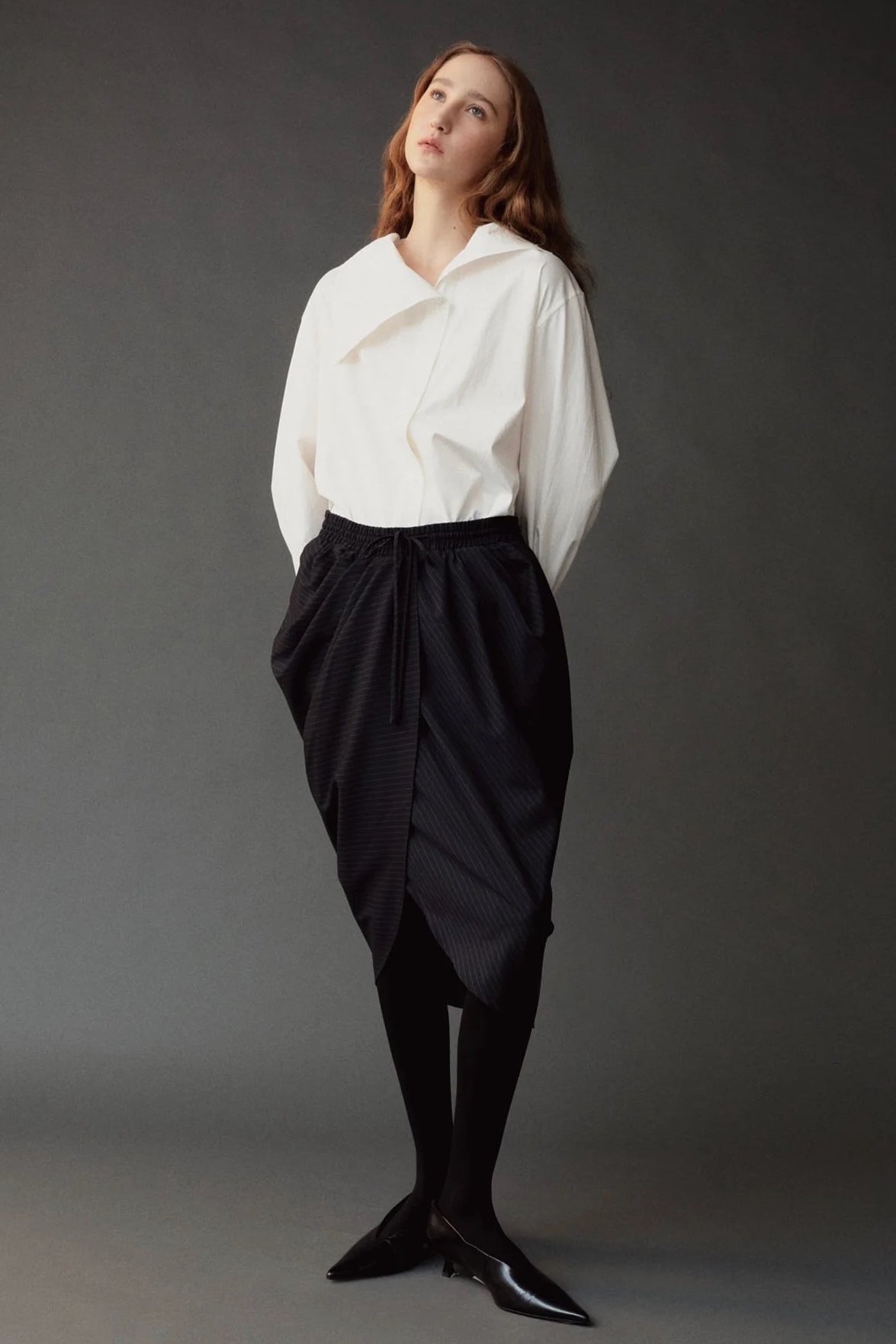 Front view of the Mijeong Park white cotton shirt styled with a draped black midi skirt