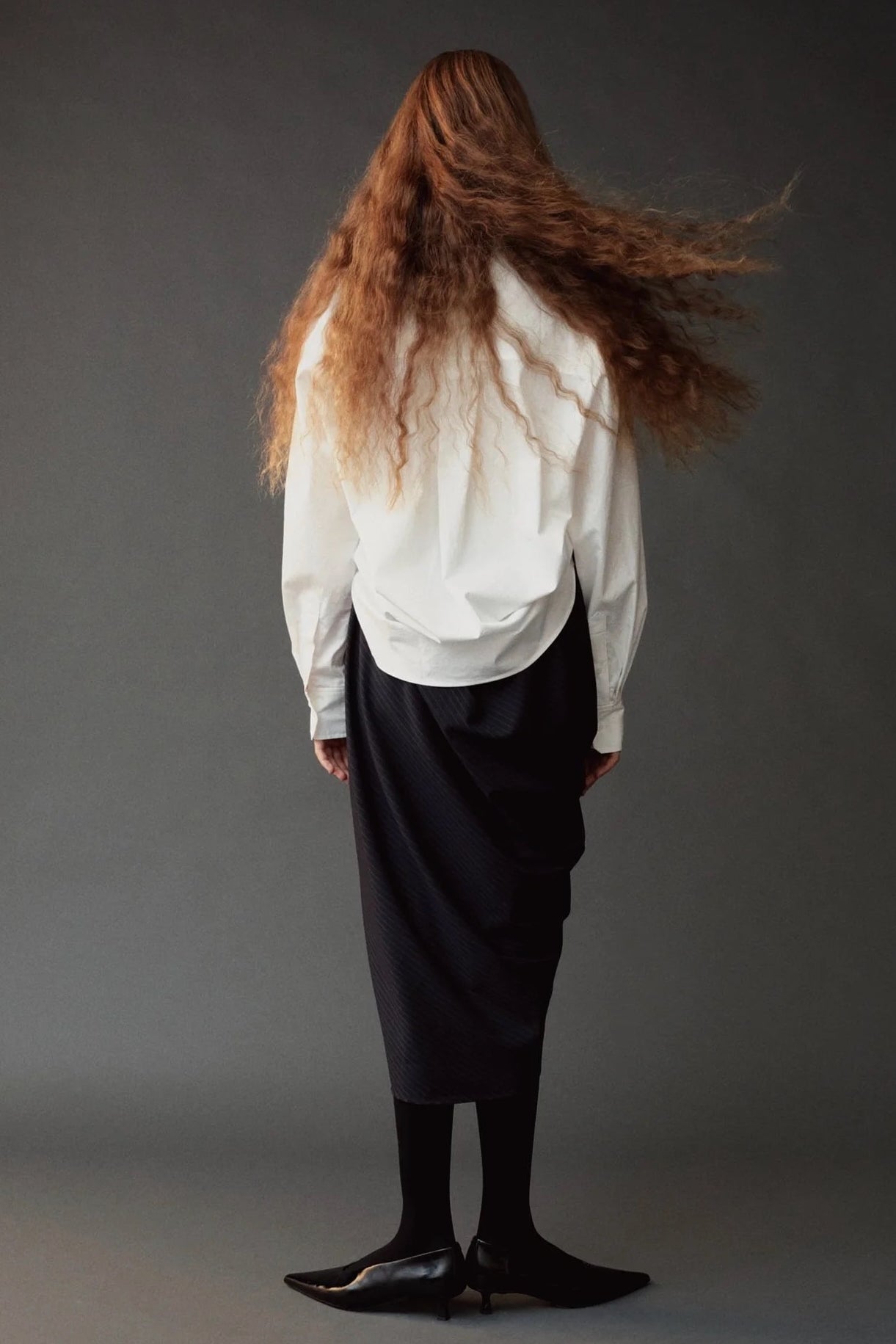 Back view of the Mijeong Park Asymmetric Cotton Shirt in white showing its rounded hem