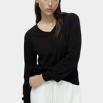 Cotton blend v neck knit top in black by Mijeong Park styled with white wide leg pants