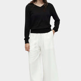 Cotton blend v neck knit top in black by Mijeong Park styled with white wide leg pants