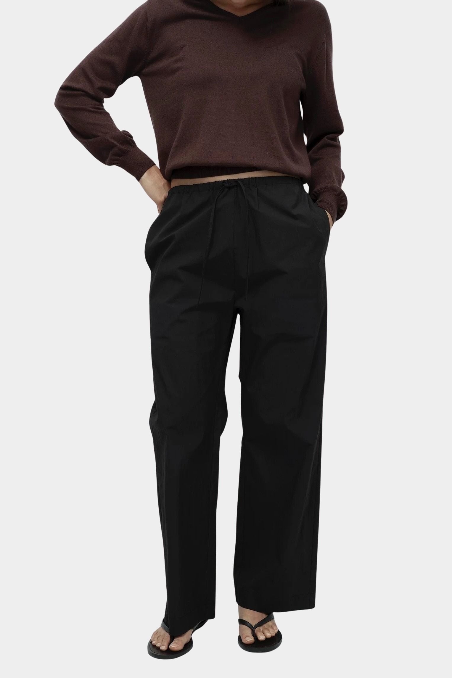 Detail of brown cotton blend v neck knit top by Mijeong Park styled with relaxed black trousers