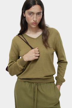 Green cotton blend v neck knit top by Mijeong Park with relaxed fit styled with matching knit pants