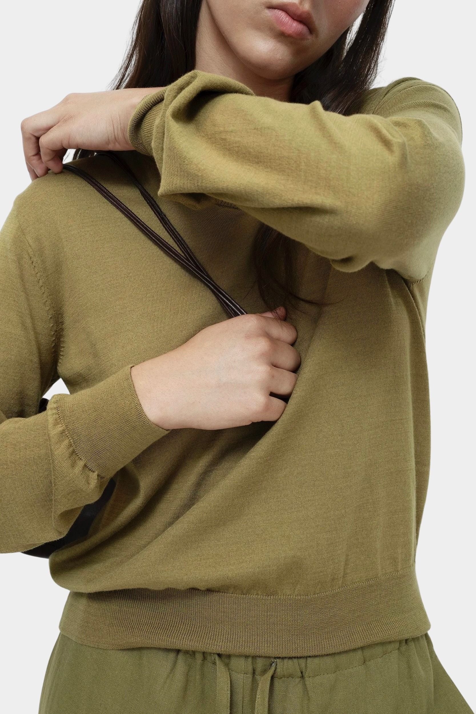 Detail of green cotton blend v neck knit top by Mijeong Park showing sleeve cuff and lightweight knit texture