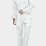 White cotton blend v neck knit top by Mijeong Park styled with white wide leg trousers
