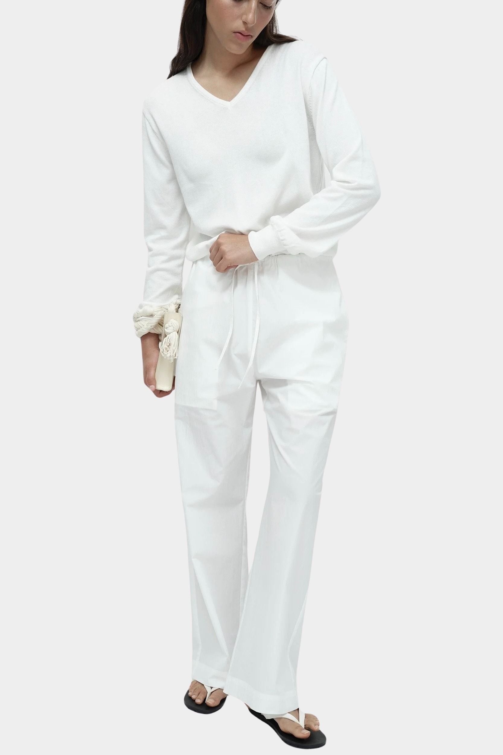 White cotton blend v neck knit top by Mijeong Park styled with white wide leg trousers