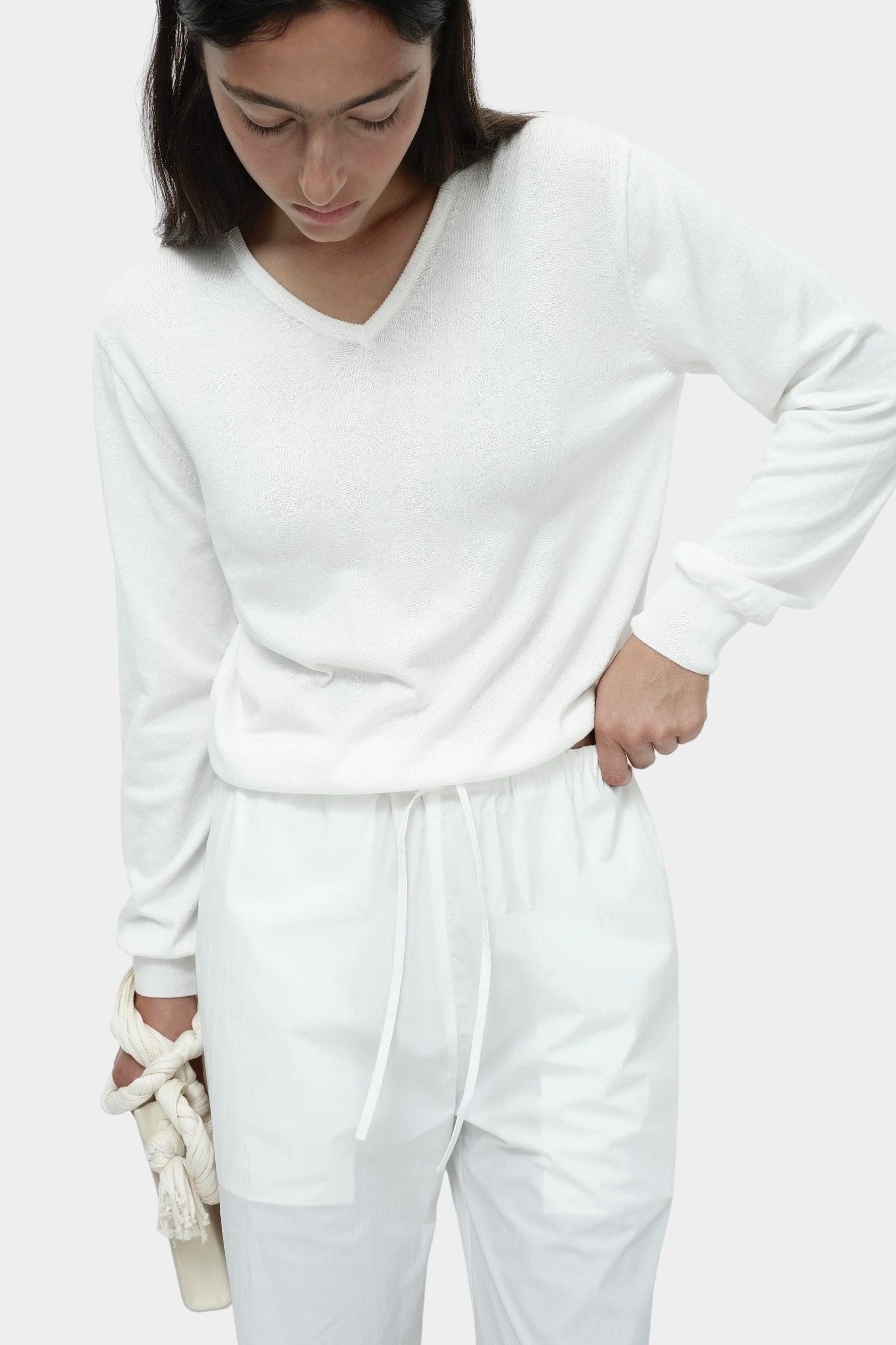 White cotton blend v neck knit top by Mijeong Park with relaxed fit styled with white drawstring trousers
