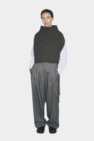 Model wearing charcoal ribbed knit neck warmer vest with high funnel neck and side ties