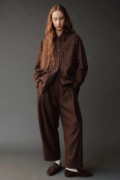 Model wearing the Mijeong Park Oversized Plaid Shirt in brown plaid with relaxed brown trousers