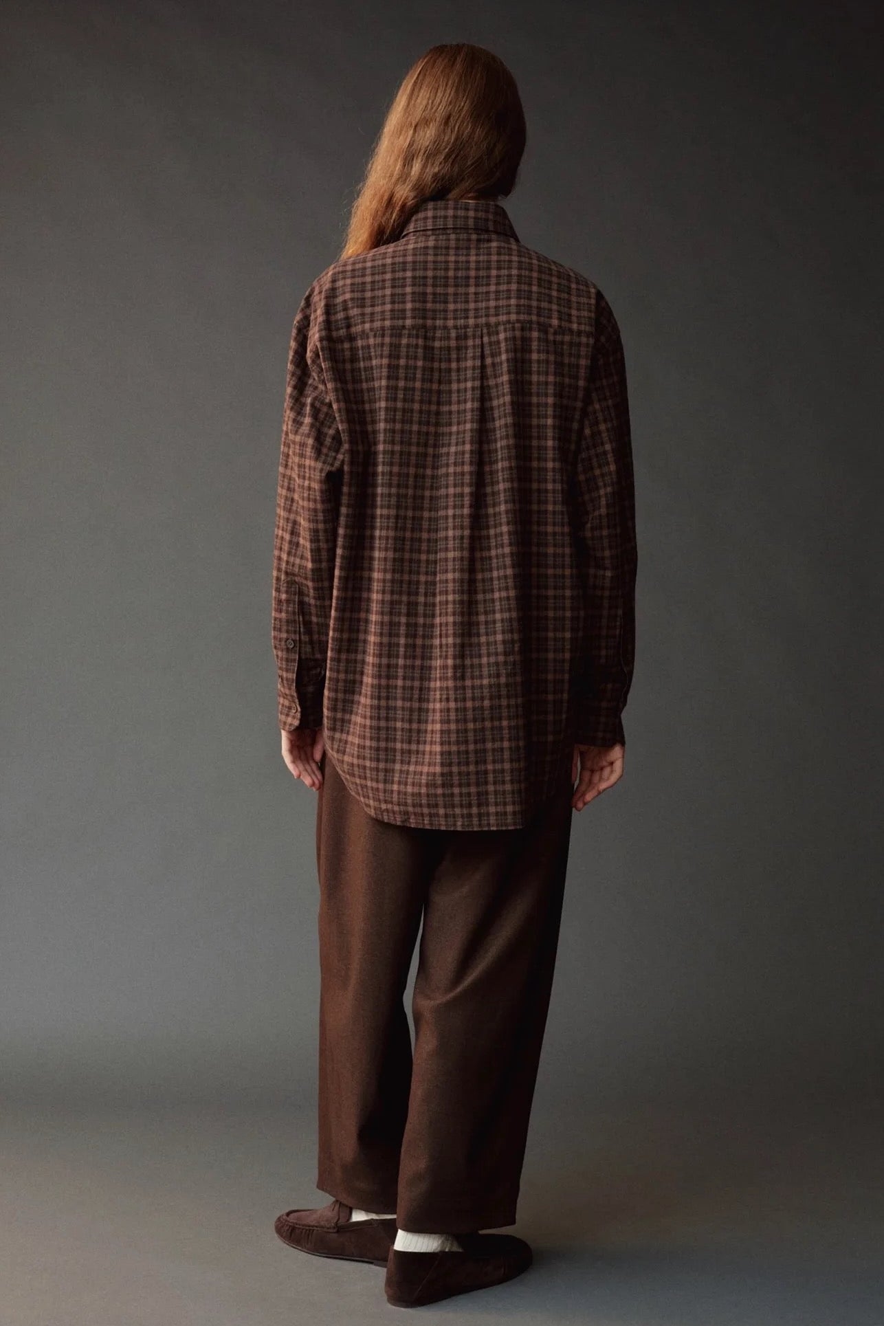 Back view of the Mijeong Park brown plaid shirt showing its oversized silhouette and curved hem