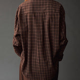 Close back view of the Mijeong Park Oversized Plaid Shirt showing the center pleat and curved hem