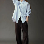 Model wearing the Mijeong Park Oversized Shirt in light blue with relaxed dark trousers