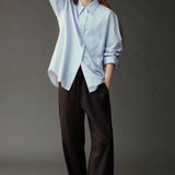 Model wearing the Mijeong Park Oversized Shirt in light blue with relaxed dark trousers