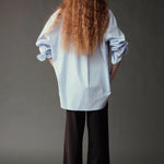 Back view of the Mijeong Park light blue shirt showing its oversized silhouette and long curved hem