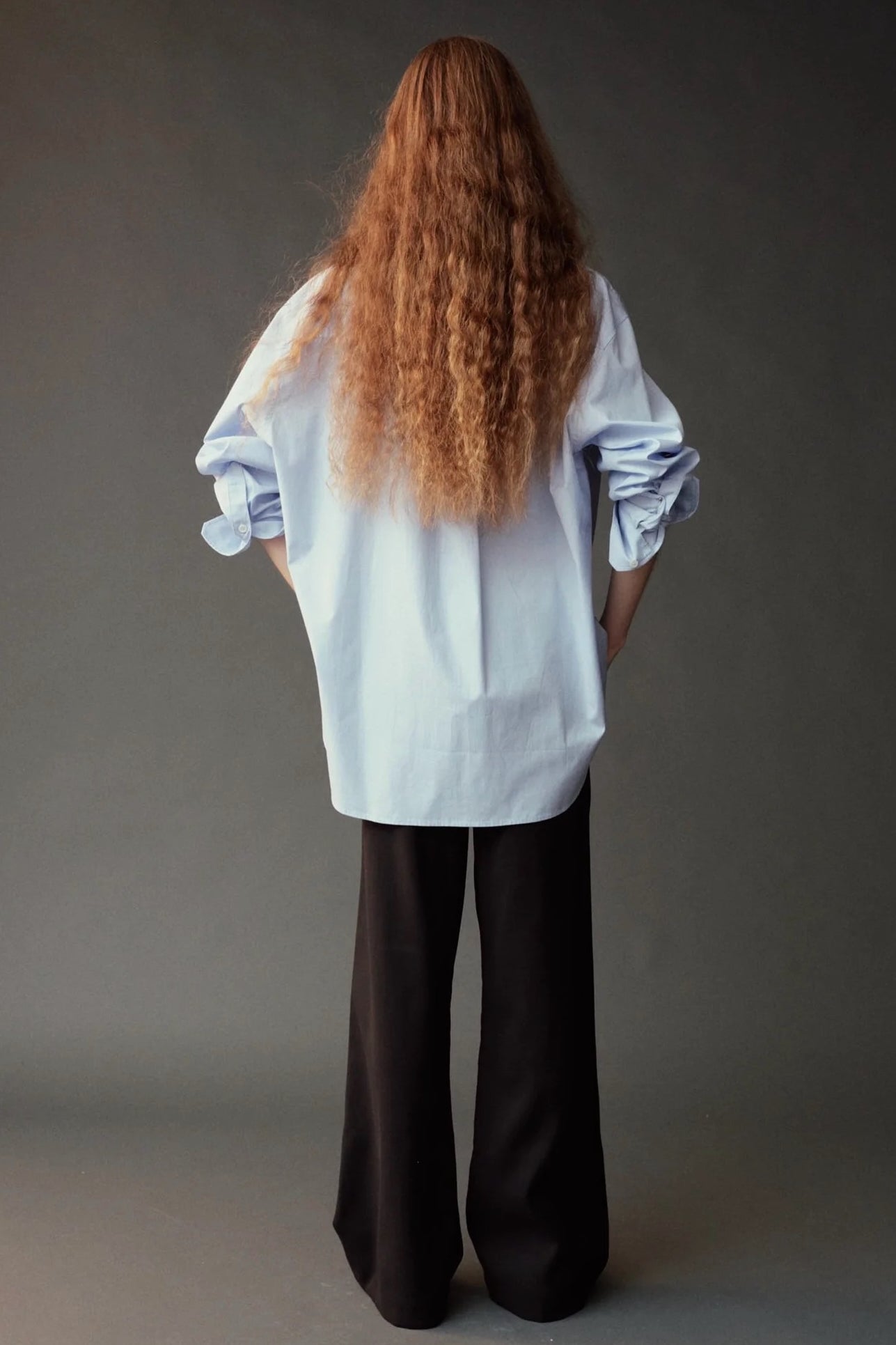 Back view of the Mijeong Park light blue shirt showing its oversized silhouette and long curved hem