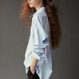 Side view of the Mijeong Park light blue oversized shirt styled with dark wide leg trousers