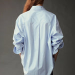 Back view of the Mijeong Park Oversized Shirt in light blue with rolled sleeves and a curved hem