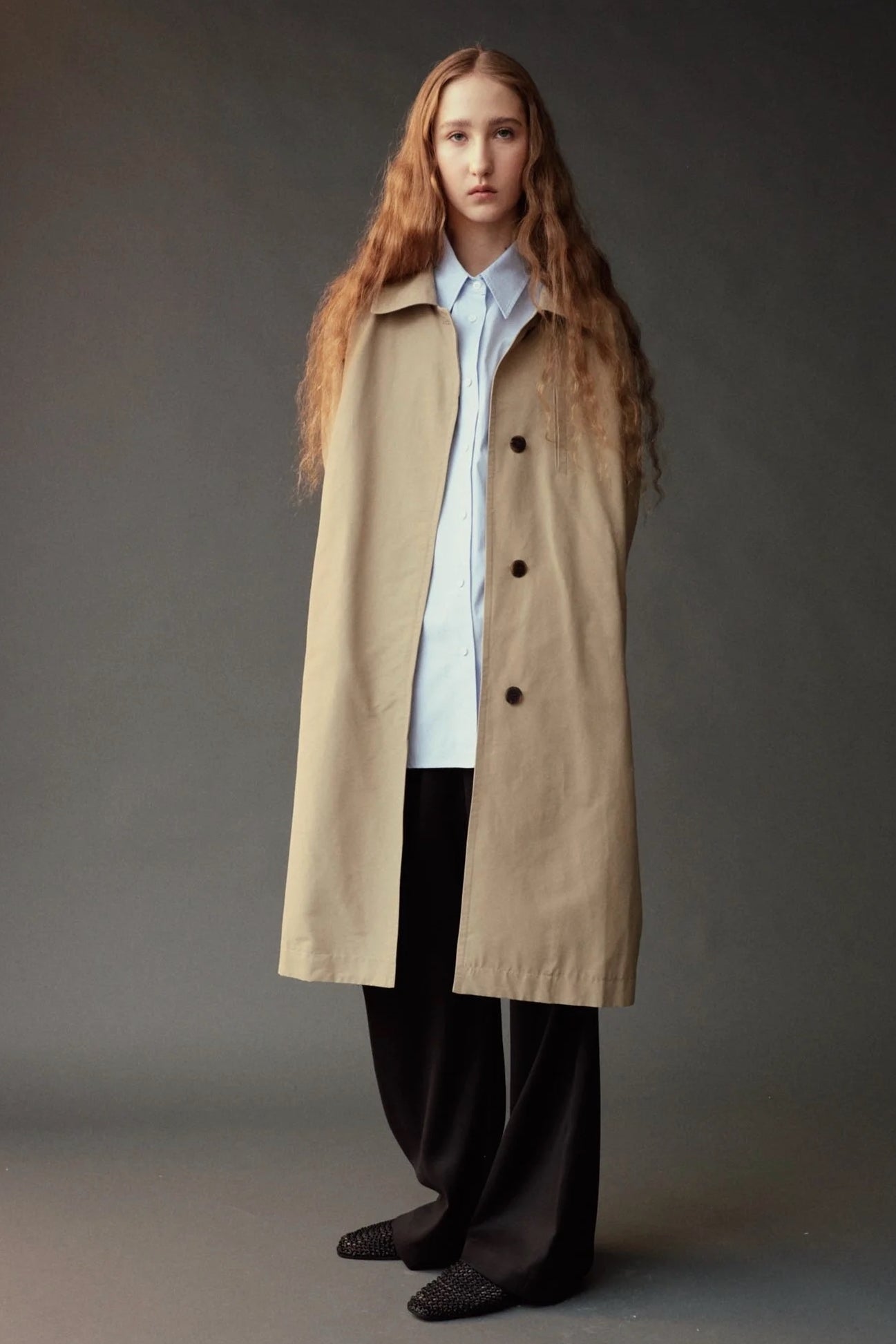 Mijeong Park Oversized Shirt in light blue layered beneath a long beige coat with wide leg trousers