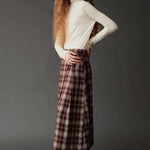 Side view of model wearing the Mijeong Park Plaid Midi Skirt in brown plaid with an ivory turtleneck